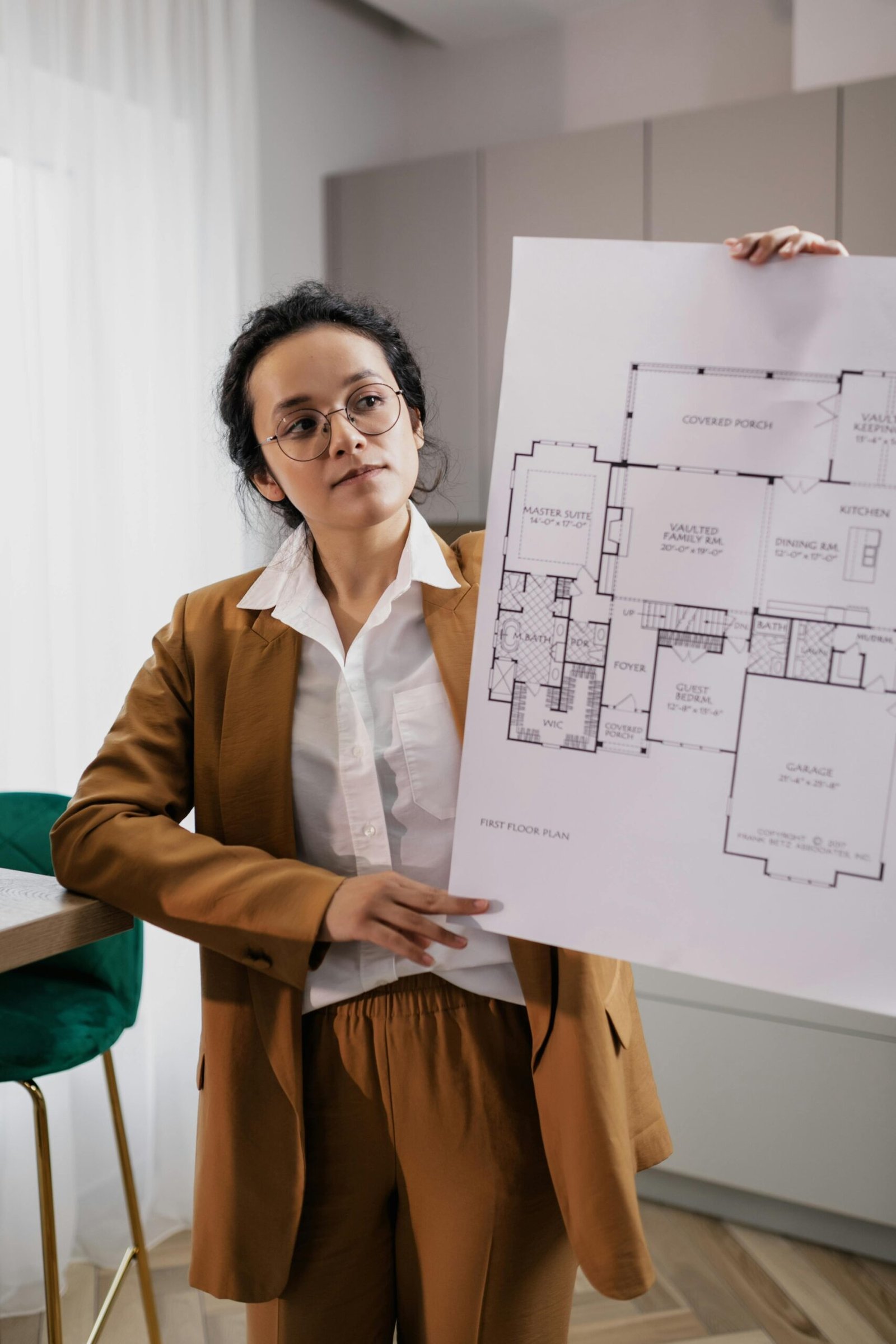 A Woman Wearing Business Attire Holding a Paper with a House Floor Plan